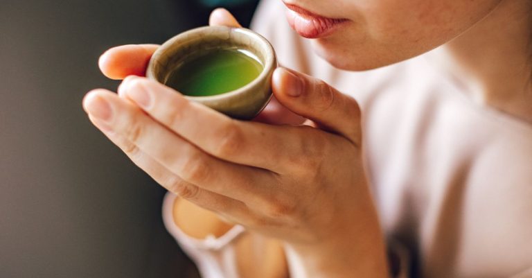 Close-up of a woman enjoying a hot matcha tea, highlighting a healthy lifestyle.