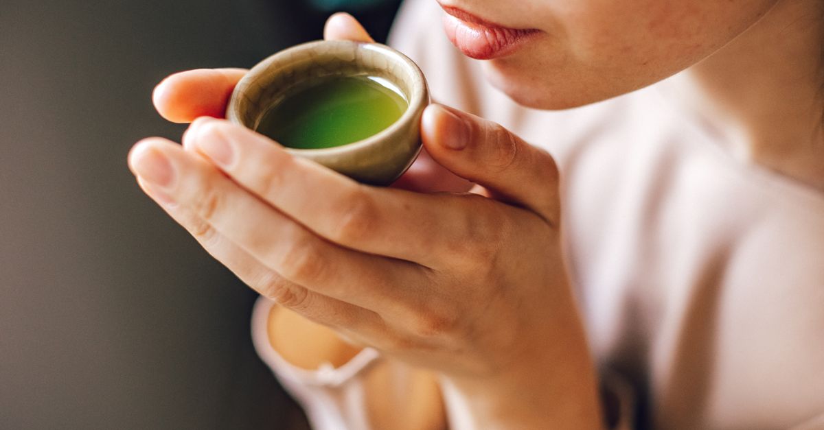Close-up of a woman enjoying a hot matcha tea, highlighting a healthy lifestyle.