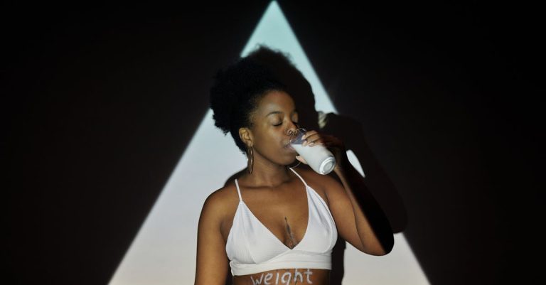 A woman in a studio drinking milk with 'weight loss' written, conveying health and wellness.