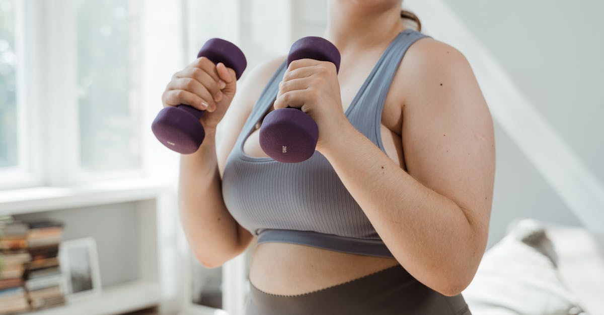Plus size woman in activewear working out with dumbbells indoors, promoting body positivity.