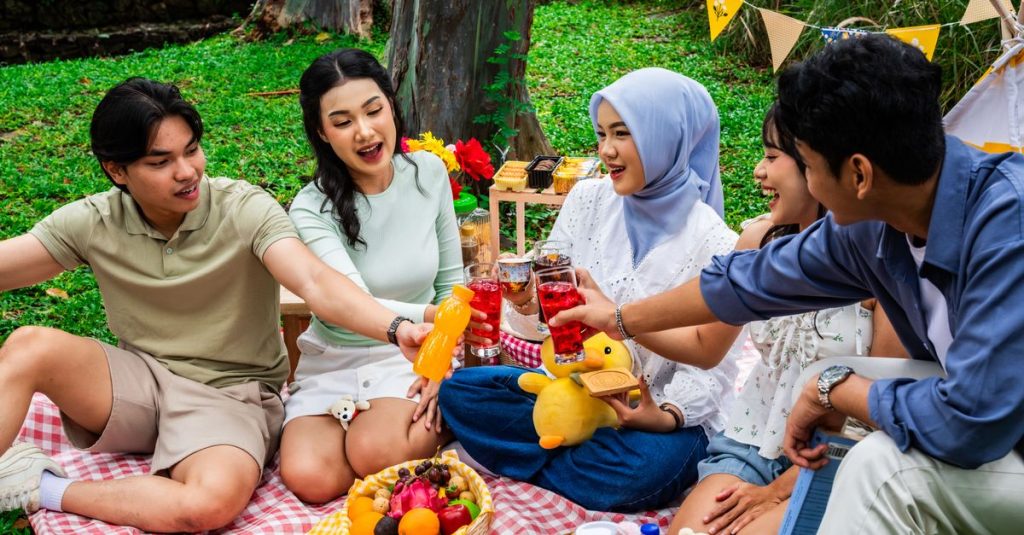 A group of friends enjoying a colorful picnic outdoors in Indonesia, celebrating friendship with snacks and drinks.