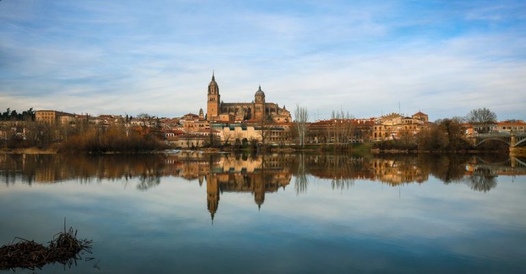 Capture of Salamanca Cathedral reflecting in Tormes River on a clear day, showcasing the historic architecture.