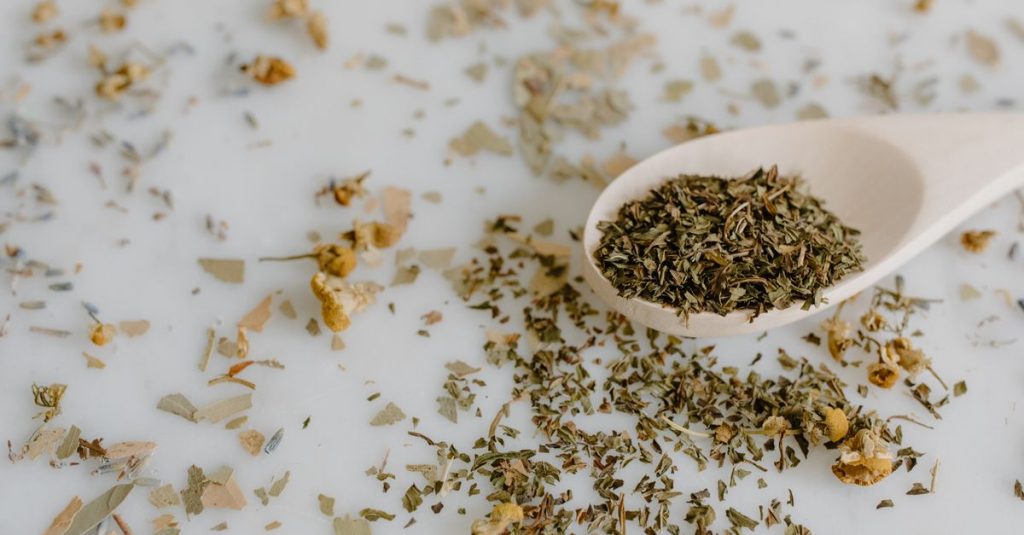 Close-up of dried herbs and floral elements with wooden spoon.