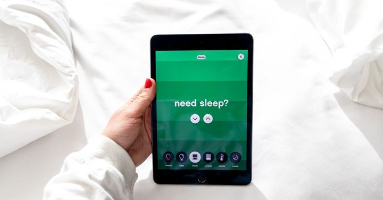 A close-up of a hand holding a tablet displaying a sleep app interface in bright daylight.