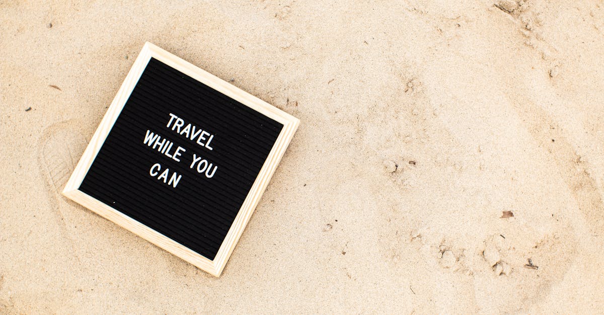 Letter board with 'Travel While You Can' message displayed on sandy beach scene, inspiring wanderlust.