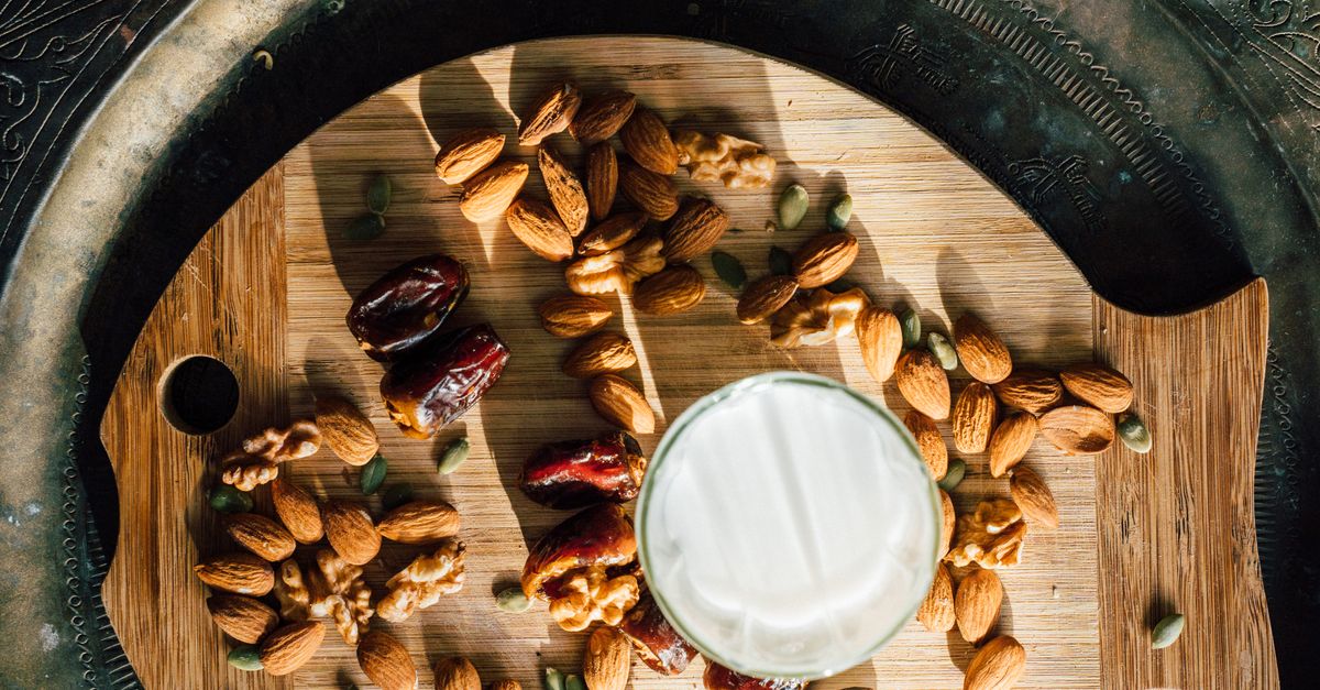 Flat lay of almonds, dates, and milk for iftar on a wooden board.