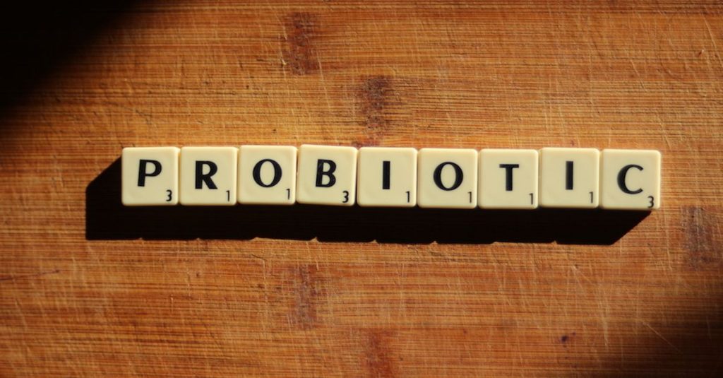 Close-up of the word 'probiotic' crafted from letter tiles on a wooden surface.
