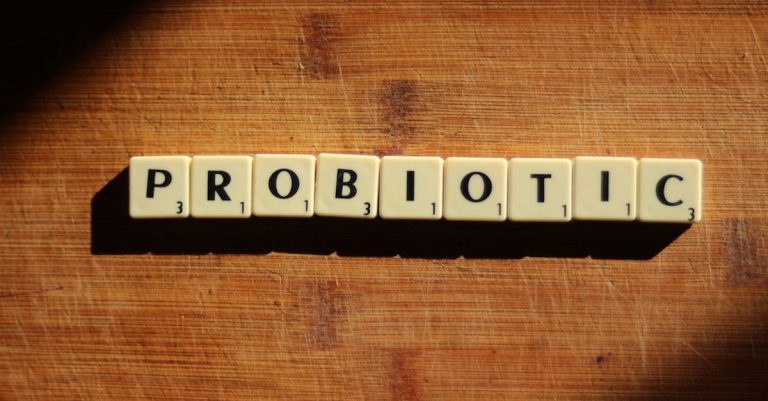 Close-up of the word 'probiotic' crafted from letter tiles on a wooden surface.