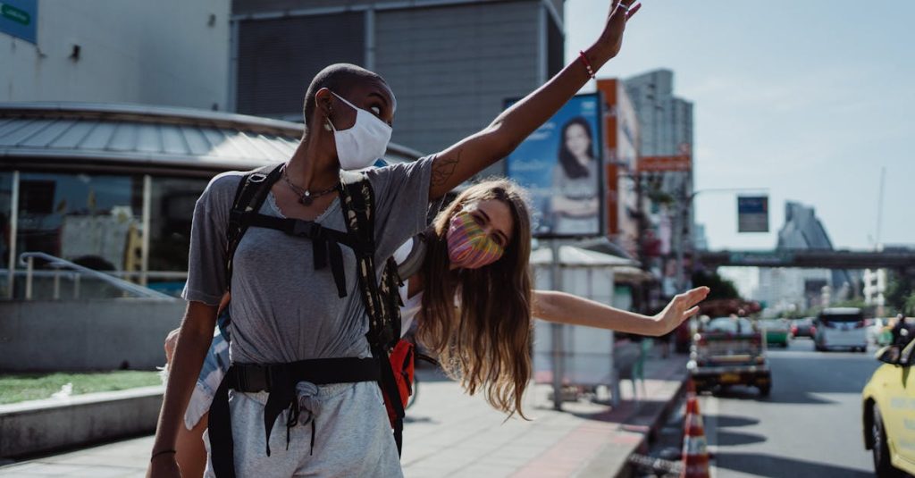 Two friends with backpacks waving in a bustling city, embracing travel adventure with safety masks.
