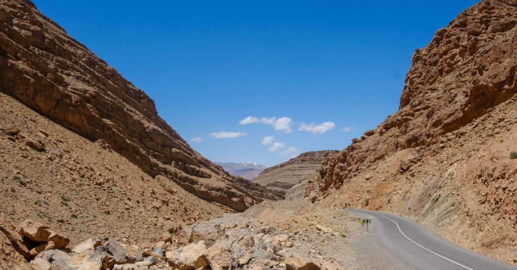 A breathtaking view of a winding road through the rocky Atlas Mountains under a clear blue sky in Morocco.
