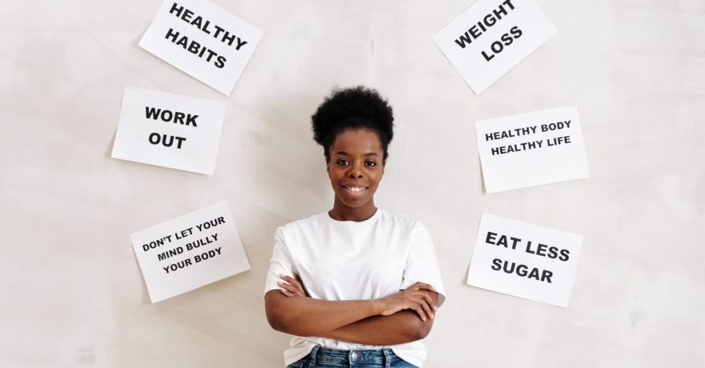 Confident woman poses with motivational health messages on the wall for wellbeing.